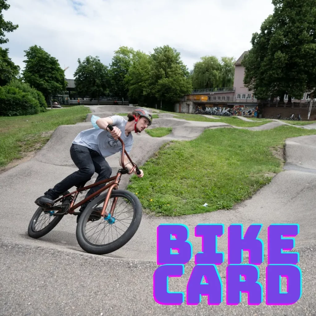 Ein Jugendhausmitarbeiter fährt mit einem BMX-Rad auf der Pumptrack, ein schmaler asphaltierter Parkours mit kniehohen Hügeln, welcher sich beim Jugendhaus neben dem Sportplatz befindet.